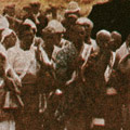 Postcard: People standing before a large mound of ashen human remains at the site of Honjo Clothing Depot